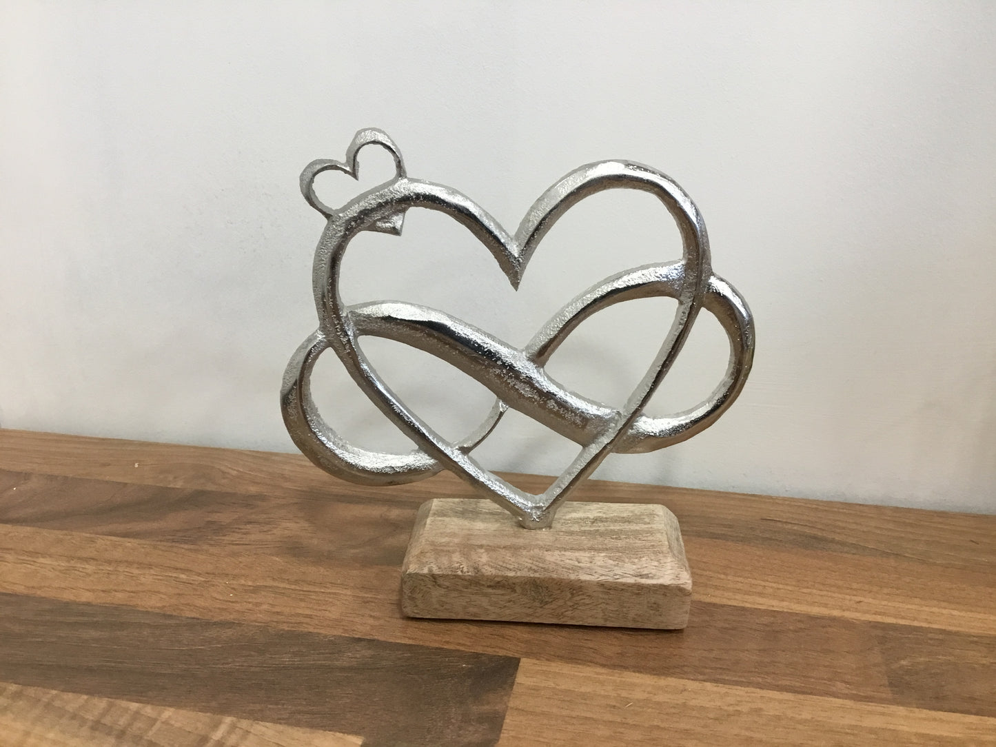 Entwined metal hearts on wooden base